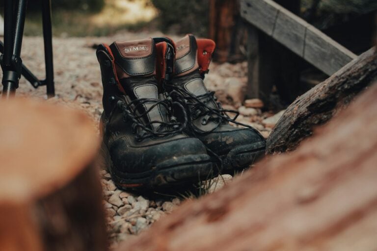 Rugged hunting boots on gravel next to firewood