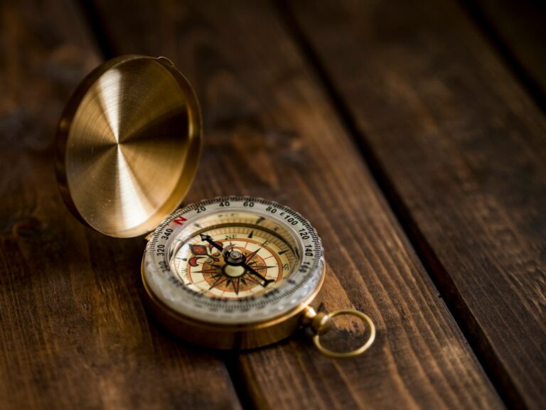 Vintage brass compass open on a dark wooden table